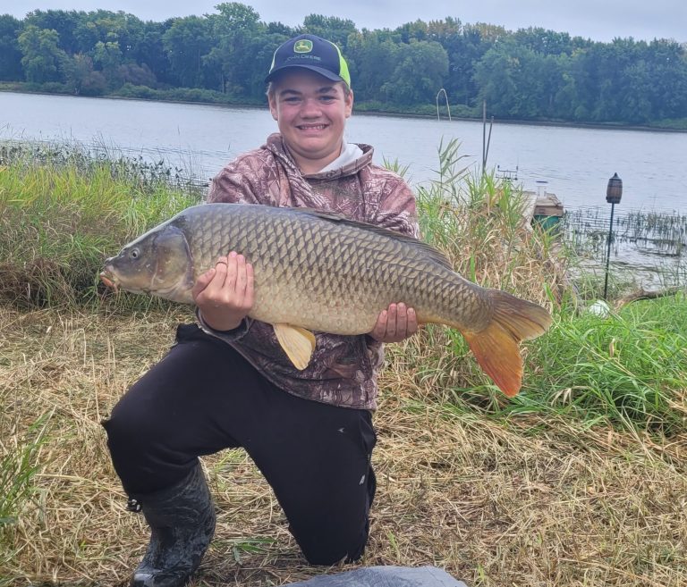 Enfant portant une carpe sur le bord d'une rivière